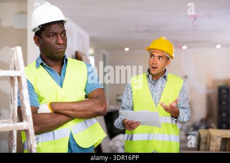 Portrait of confused man builder quarreling with co-worker Stock Photo