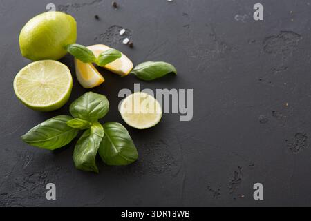 Fresh Lime and Basil Arranged on Dark Surface With Slices and Leaves Stock Photo