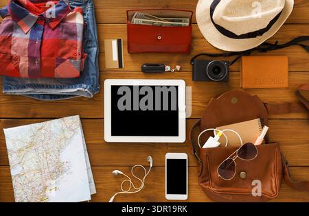 Travel Preparation With Clothes, Gadgets, and a Map Laid out on a Wooden Table Stock Photo