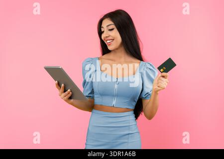 Excited young woman holding credit card and tablet Stock Photo