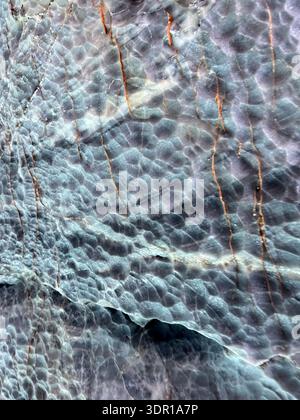 Close-up detail of natural marble stone surface showing intricate mineral veining, subtle tonal variations, and irregular crystalline structure. Stock Photo