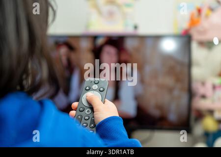 Child Holding a Smart TV Remote Control at Home Stock Photo