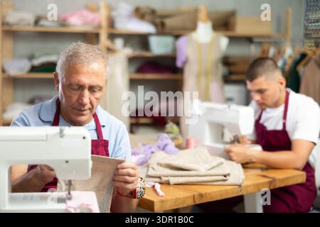 Two male tailors working with fabric Stock Photo