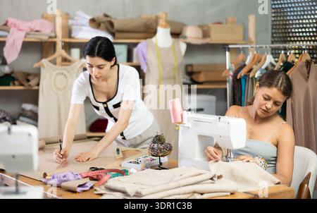 Two female tailors working on custom garment in studio Stock Photo