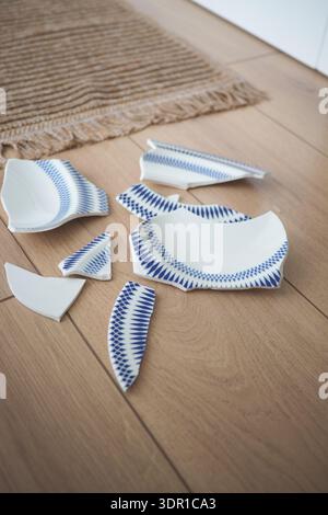 Broken pieces of a ceramic plate on wooden floor Stock Photo
