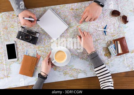 Group Planning a Trip With Map, Notes, and Coffee on a Wooden Table Stock Photo