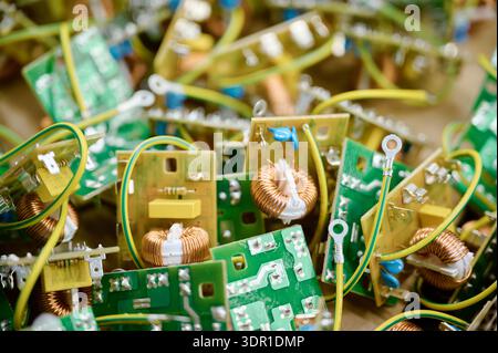 Colorful circuit boards with coils and connectors are spread out on a table in a workshop illustrating electronic components Stock Photo
