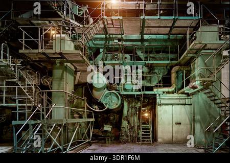 Industrial machinery in a large facility showcasing complex structures and extensive piping systems during nighttime operations Stock Photo
