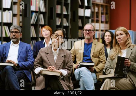 Diverse Group of Diverse Adults Attending Book Presentation in Library Stock Photo