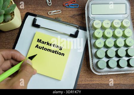 Concept of marketing automation write on sticky notes isolated on Wooden Table. Stock Photo