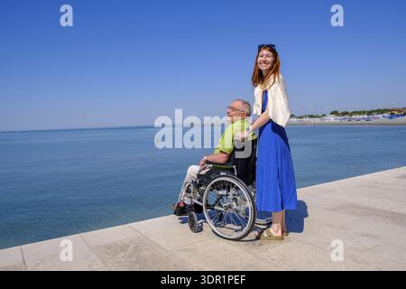 Senior in wheelchair looking at the sea, vacation with a handicap, Grado, Julian-Friuli, Adriatic Sea, Italy Stock Photo