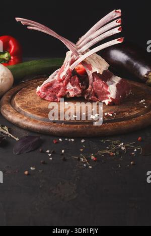 Fresh Meat Cuts on a Wooden Board With Vegetables in a Dark Kitchen Setting Stock Photo