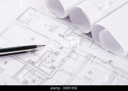 Collection of Architectural Plans and Blueprints With Rolled Papers and Pens on a White Background Stock Photo