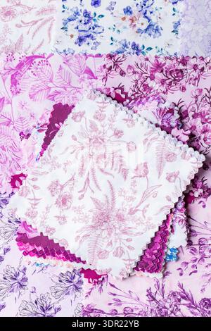 Fabric patchwork squares, in various colours and designs, stacked background backdrop. Sewing craft needlework concept. Stock Photo