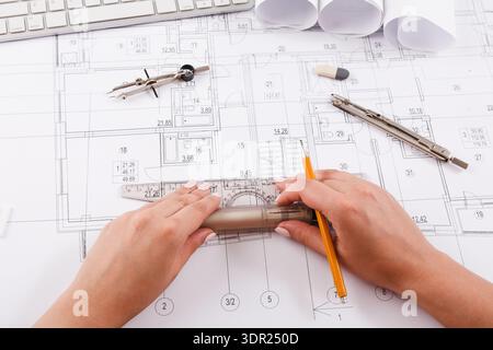 Hands Working on a Design Layout With Tools and Keyboard on a Table in an Office Setting Stock Photo