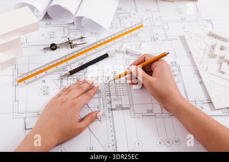 Drawing a Detailed Plan With Tools on a Large Sheet of Architectural Design Stock Photo