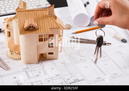 Collage of House Model and Keys on Construction Plans at Design Workspace Stock Photo
