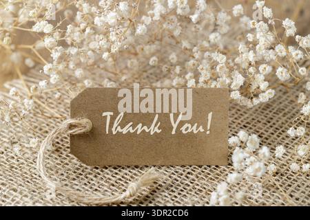 Vintage Thank you card with dried white flowers on jute background. Stock Photo