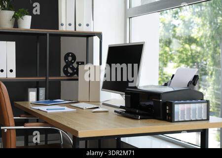 Modern workplace with computer and printer near window in office Stock Photo