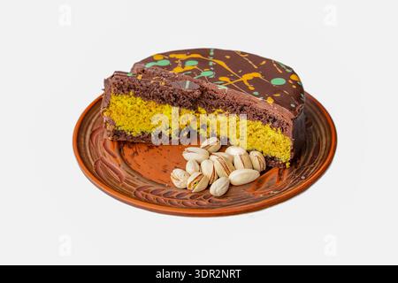 Chocolate pistachio layer cake slice on ceramic plate with whole pistachio nuts Stock Photo