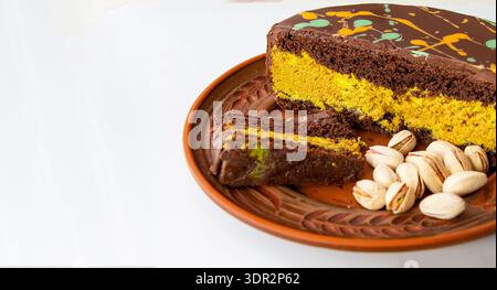 Chocolate pistachio layer cake slice on ceramic plate with whole pistachio nuts Stock Photo