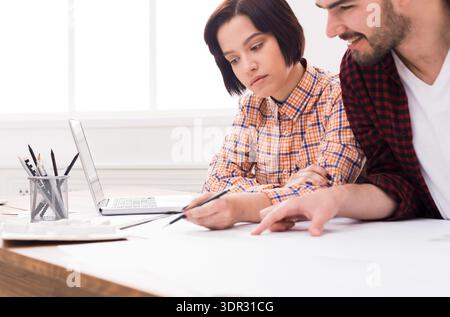 Collaborators Work on a Project at a Table With a Laptop and Drawing Tools Stock Photo