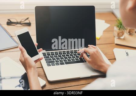 Person Using Laptop and Smartphone on a Wooden Desk During the Day Stock Photo