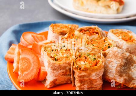 Delicious Spring Rolls Served on a Plate With Fresh Carrots and Condiments in a Kitchen Stock Photo