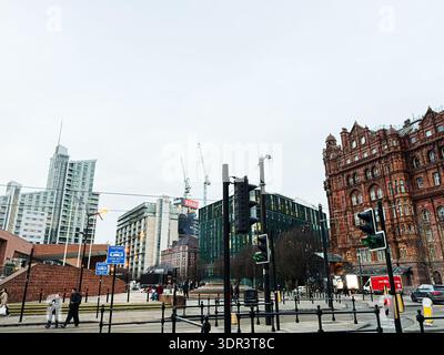 Manchester, UK - January 24, 2026: A bustling city intersection in Manchester featuring contemporary towers, historic brickwork, traffic, and pedestri Stock Photo