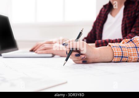People Working Together at a Desk With a Laptop and Plans in a Bright Office Stock Photo