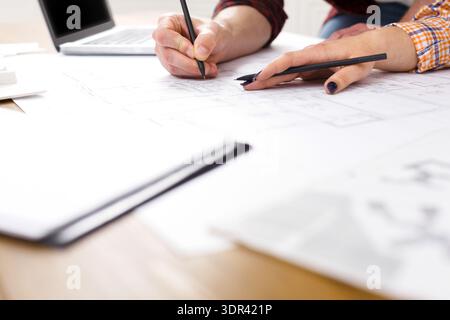 Team Members Collaborate on Design Plans at a Workspace During a Project Meeting Stock Photo