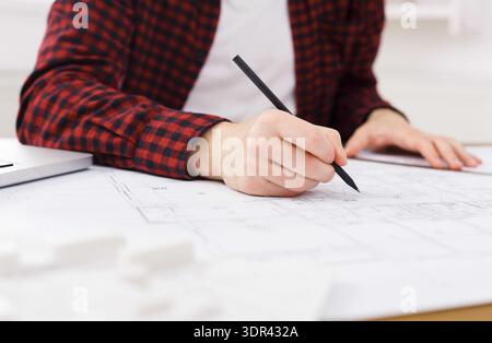 Designer Sketches Building Plans on a Table in a Bright Workspace During the Day Stock Photo