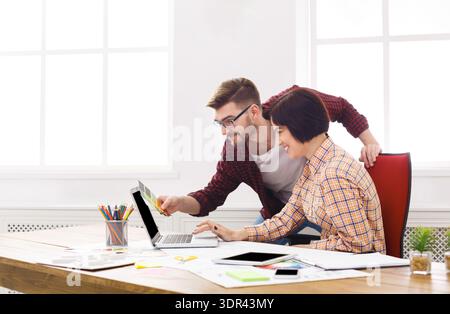 Team Members Collaborate on a Project at a Desk in a Bright Office Space During the Day Stock Photo