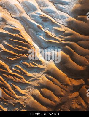 Aerial view of golden dunes sculpted by wind and time create mesmerizing patterns in the desert landscape, Kyzylkum, Mangystau Region, Kazakhstan. Stock Photo