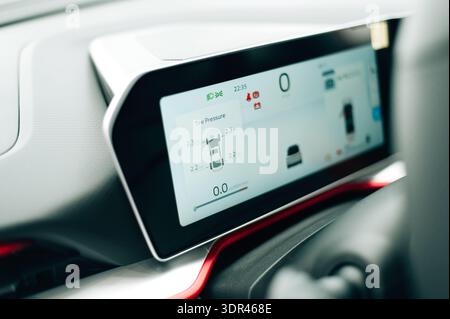 A close-up interior shot of a high-tech electric car dashboard. The large digital interface displays navigation Stock Photo