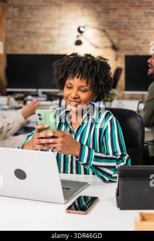Manager using smartphone and laptop at work in modern office Stock Photo