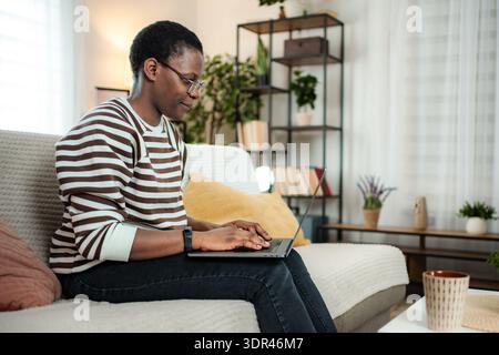 Young Black woman working remotely on laptop at home Stock Photo