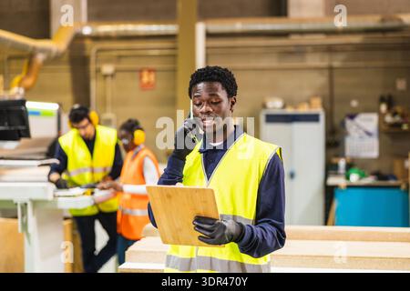 Worker having phone call in lumberyard warehouse Stock Photo