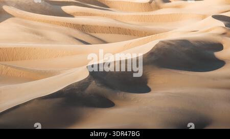 View of sun-kissed dunes rippling across the vast expanse, casting long shadows and creating a mesmerizing dance of light and shadow, Senek, Mangystau Stock Photo