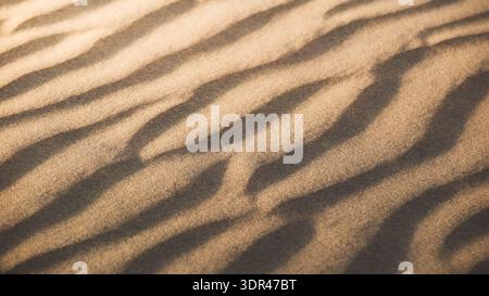 View of wind-sculpted sand dunes create hypnotic patterns of light and shadow across the desert landscape, a study in texture and form, Senek, Mangyst Stock Photo