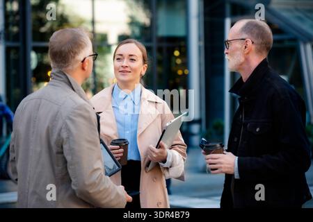 Urban business lifestyle moment: mid-age professionals meeting outdoor, collaborating with laptop and phones Stock Photo