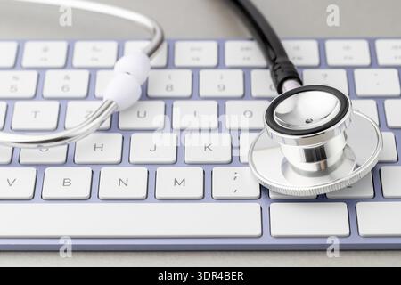 Online modern medicine or pharmacy concept. Stethoscope head on violet white keyboard on grey background. Pharmaceutical and medical help internet net Stock Photo