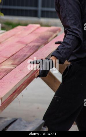 A red paint roller applying color to wooden surface with vivid texture ...