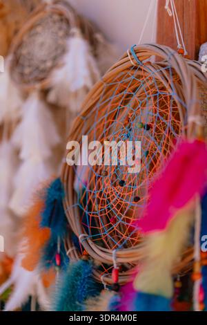 A colorful dream catcher with feathers and beads hanging from it. The feathers are in various colors and sizes, and the beads are scattered throughout Stock Photo