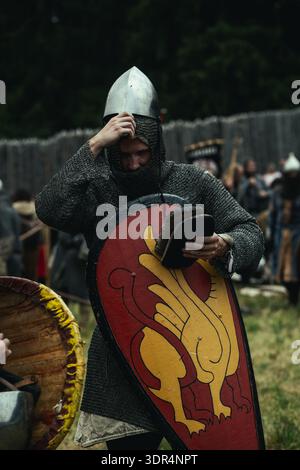 Tired warrior in chainmail armor and helmet leaning on his shield after a large-scale battle reenactment at the Utgard festival, Slovakia. Stock Photo