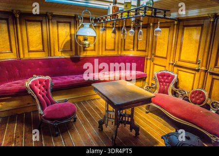 A room with a table and two red chairs. The chairs are on the left side of the room and the table is in the middle Stock Photo