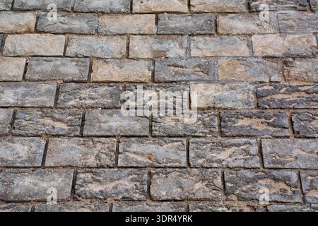 Detailed textured stone pavement background with weathered rectangular cobblestones in neutral grey and beige tones forming a rustic urban pattern ide Stock Photo