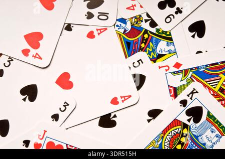 Scattered playing cards featuring ace of hearts and king of spades, gambling and poker concept close-up. Stock Photo