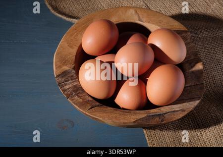 chicken eggs in gnarled wooden bowl on grey table top background Stock Photo