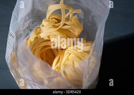 dried tagliatelle pasta in plastic packaging Stock Photo
